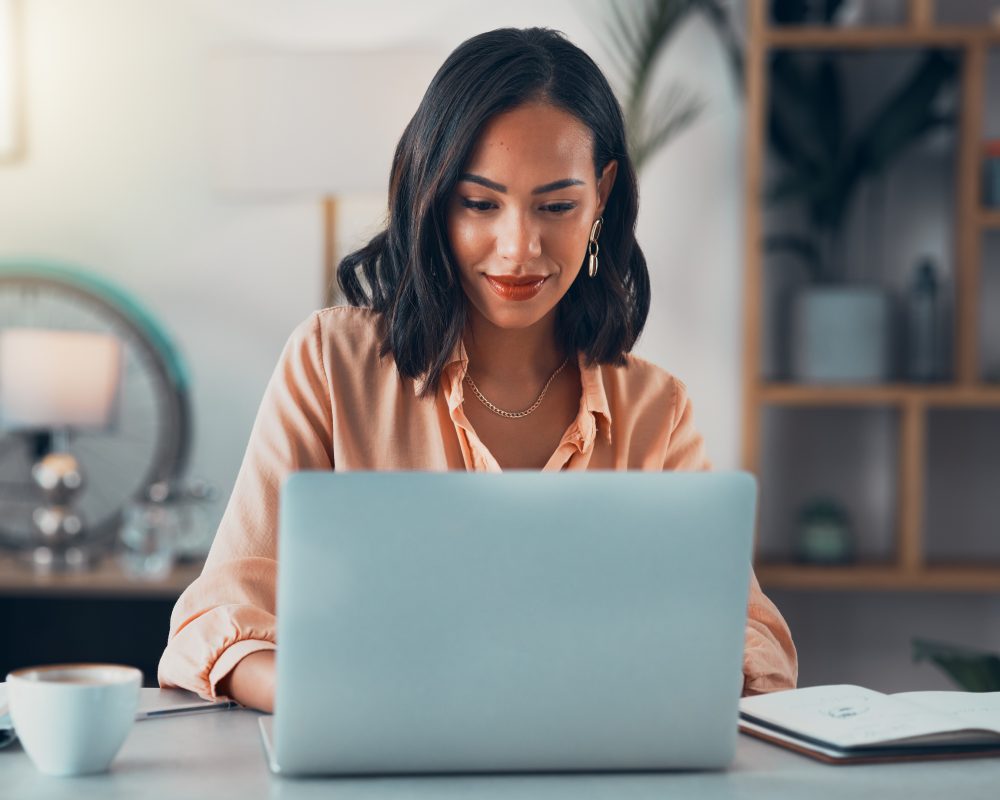 Mujer trabajando en línea en su ordenador portátil, revisando correos electrónicos y planificando en Internet mientras está sentada en una oficina sola en el trabajo. Mujer de negocios, profesional corporativa o gerente buscando en Internet.